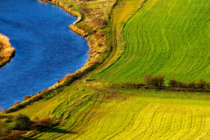 Curved patterns in mown fields set next to a winding river